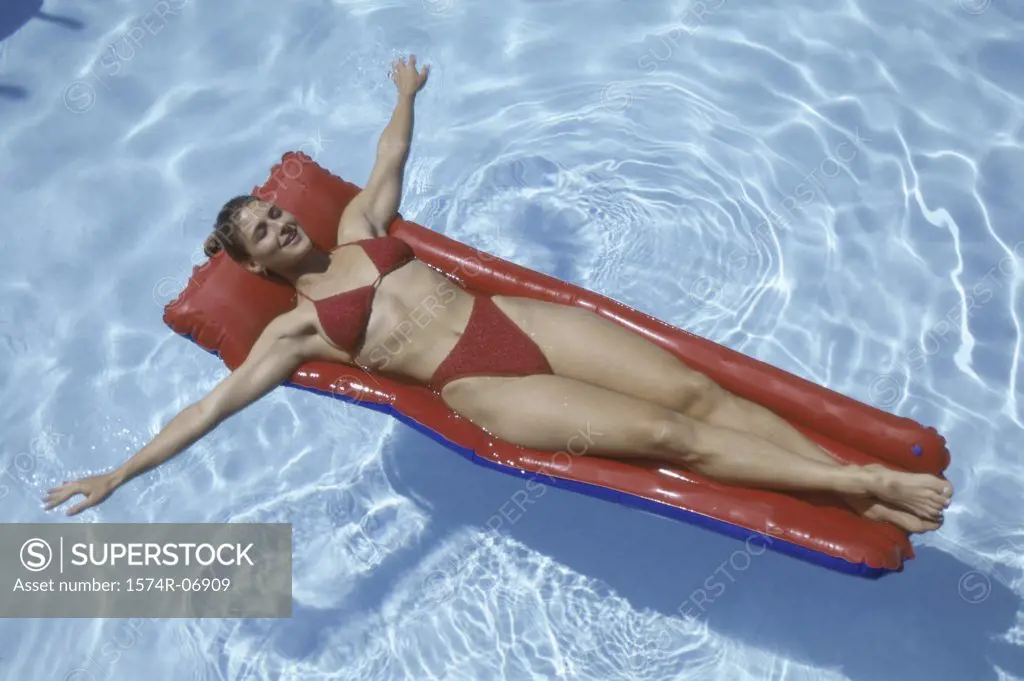 High angle view of a young woman lying on an inflatable raft in a swimming pool