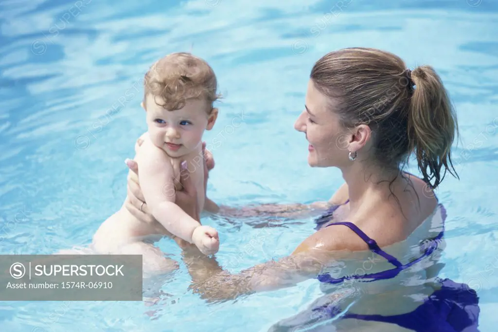 Mother holding her baby girl in a swimming pool