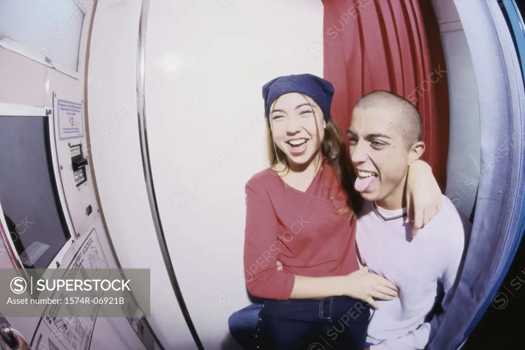 Teenage girl sitting on a teenage boy's lap in a photo booth