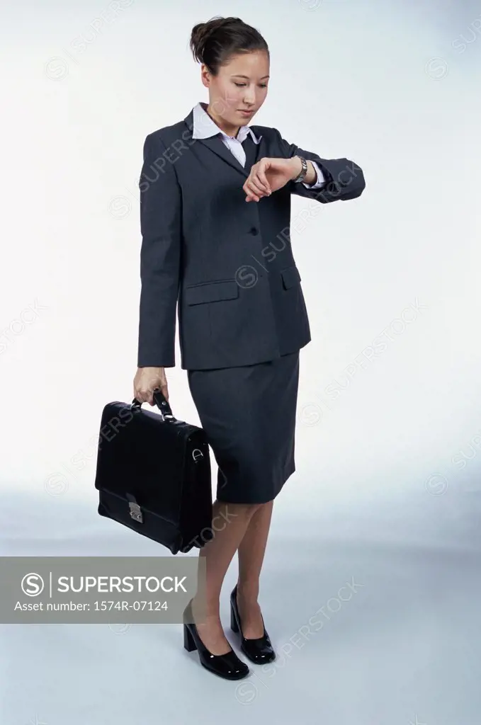Side profile of a businesswoman looking at her wristwatch holding a briefcase