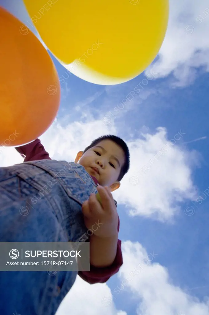 Low angle view of a boy holding balloons