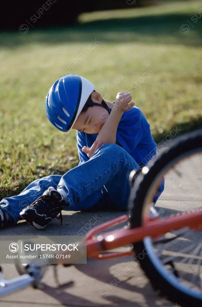Boy fallen from a bicycle holding his injured elbow
