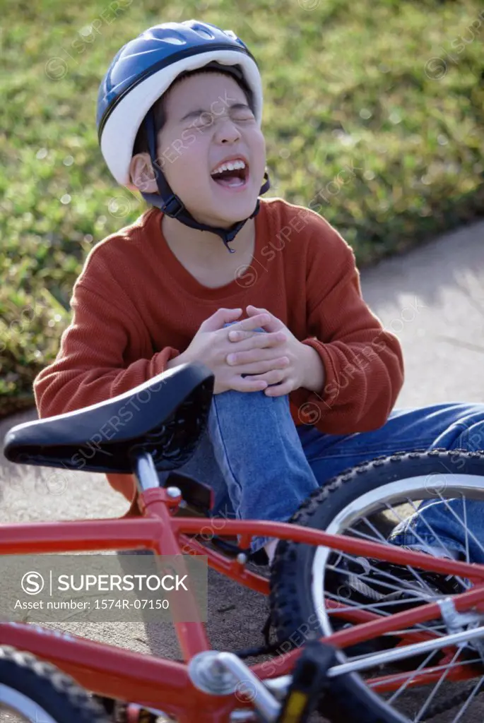 Boy fallen from a bicycle holding his injured knee