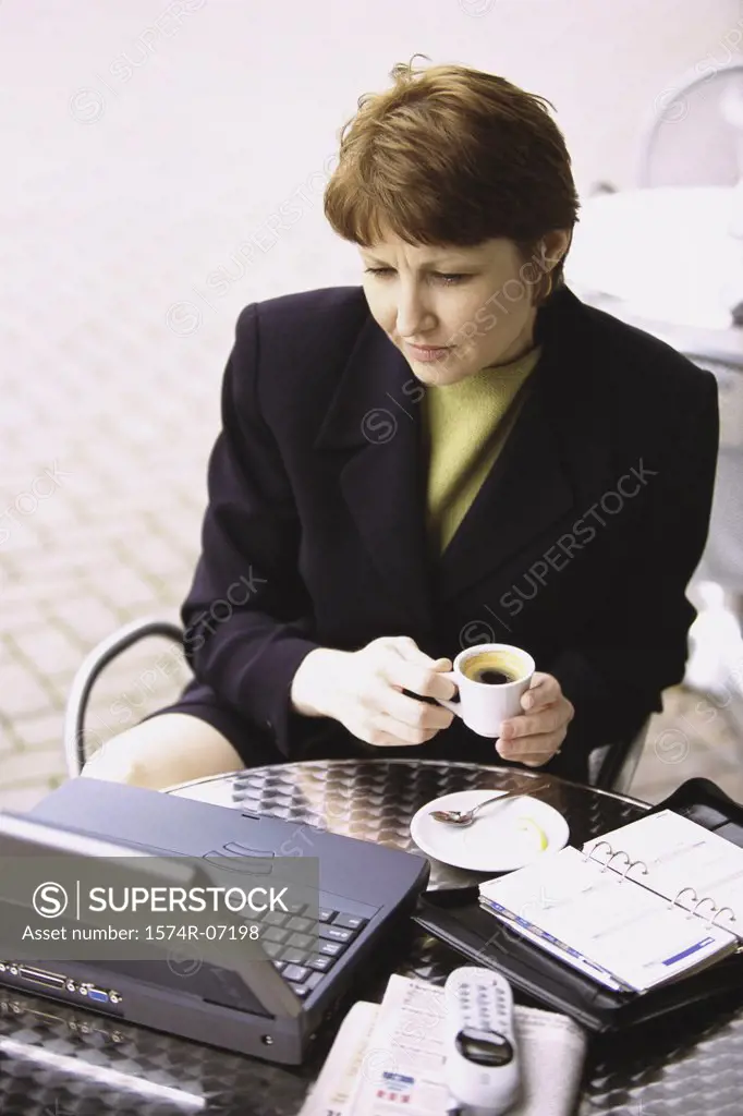 High angle view of a businesswoman holding a cup of coffee looking at a laptop