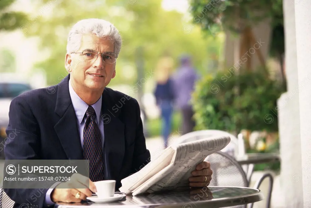 Portrait of a businessman holding a newspaper and a cup of coffee