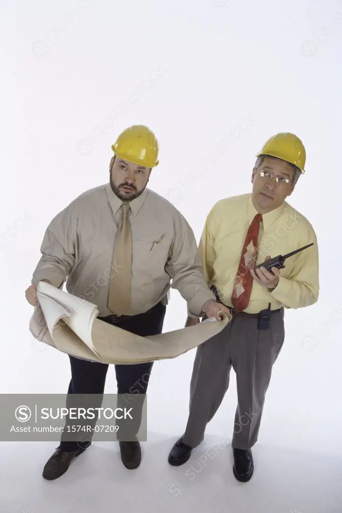 Two foremen holding walkie-talkies and blueprints