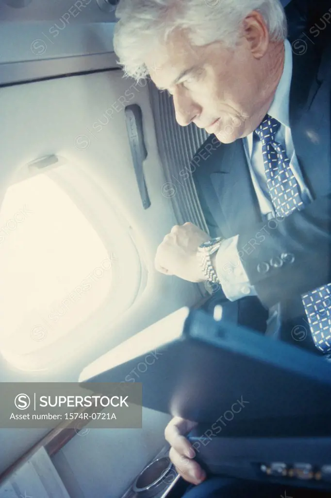 Businessman sitting in an airplane looking at his wristwatch