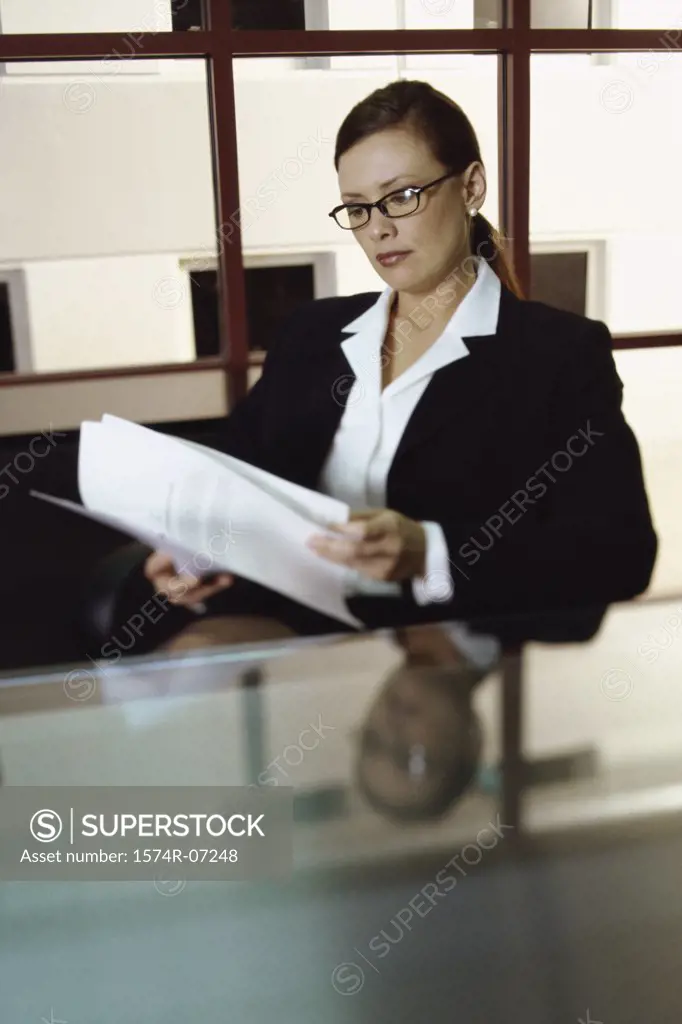Businesswoman seated at an office desk reading papers
