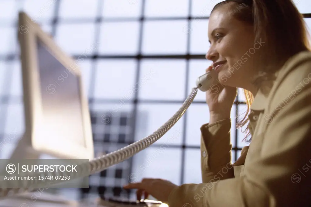 Businesswoman talking on a telephone sitting in front of a computer monitor