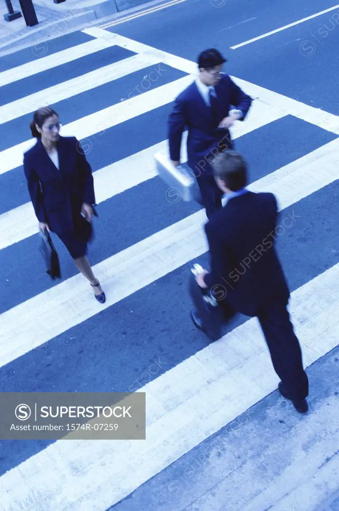 High angle view of two businessmen and a businesswoman crossing the street