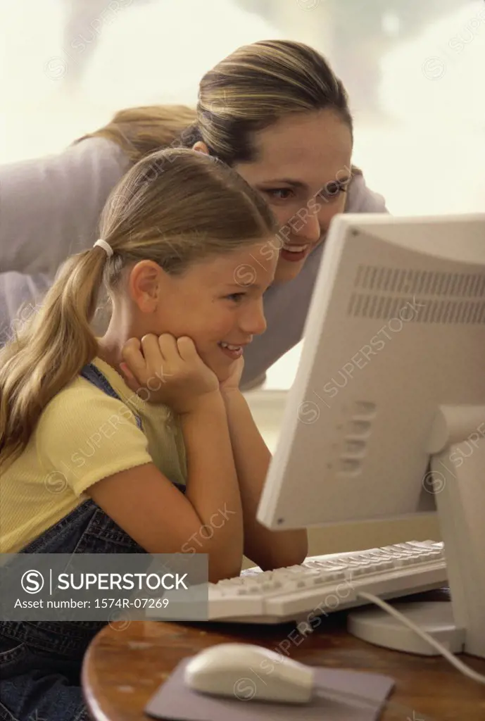 Mother and her daughter in front of a computer monitor