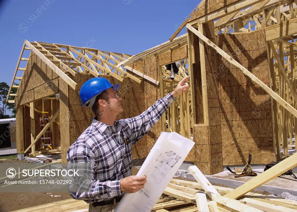 Foreman standing at a construction site holding blueprints