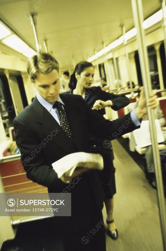 Businessman and a businesswoman standing in a train