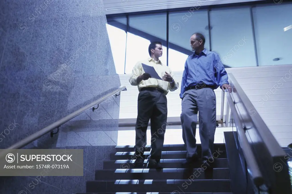 Low angle view of two businessmen walking down stairs
