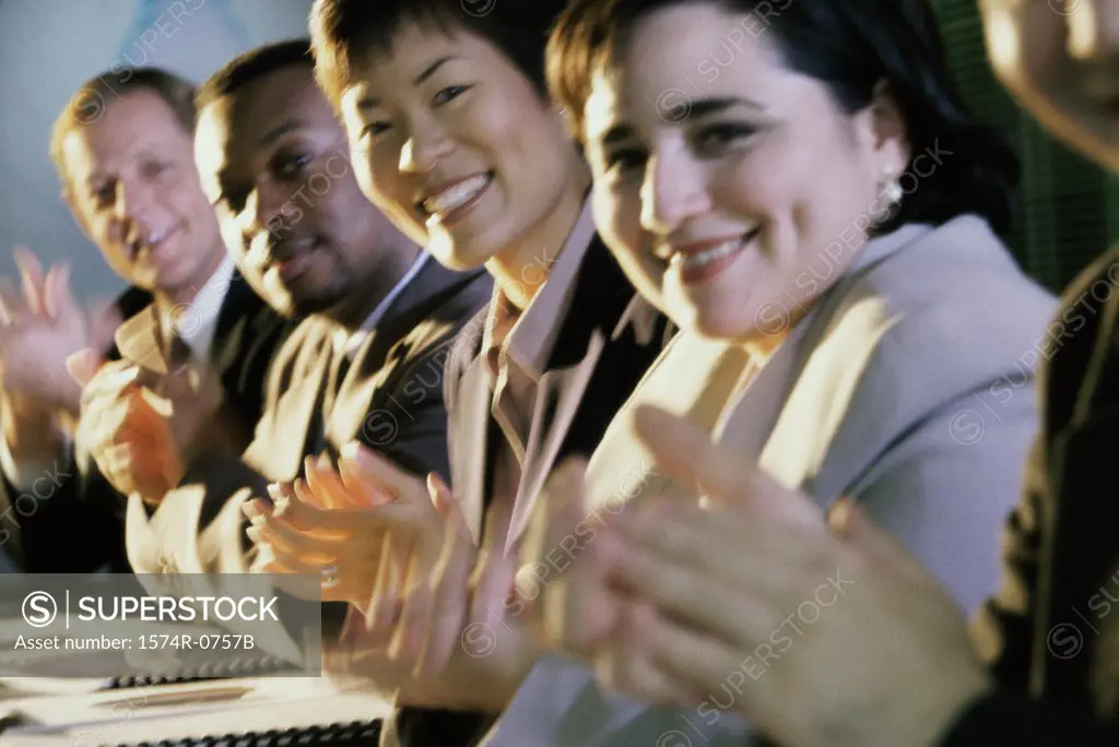 Portrait of a group of business executives applauding in a meeting