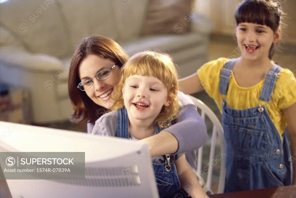 Mother and her two daughters in front of a computer monitor