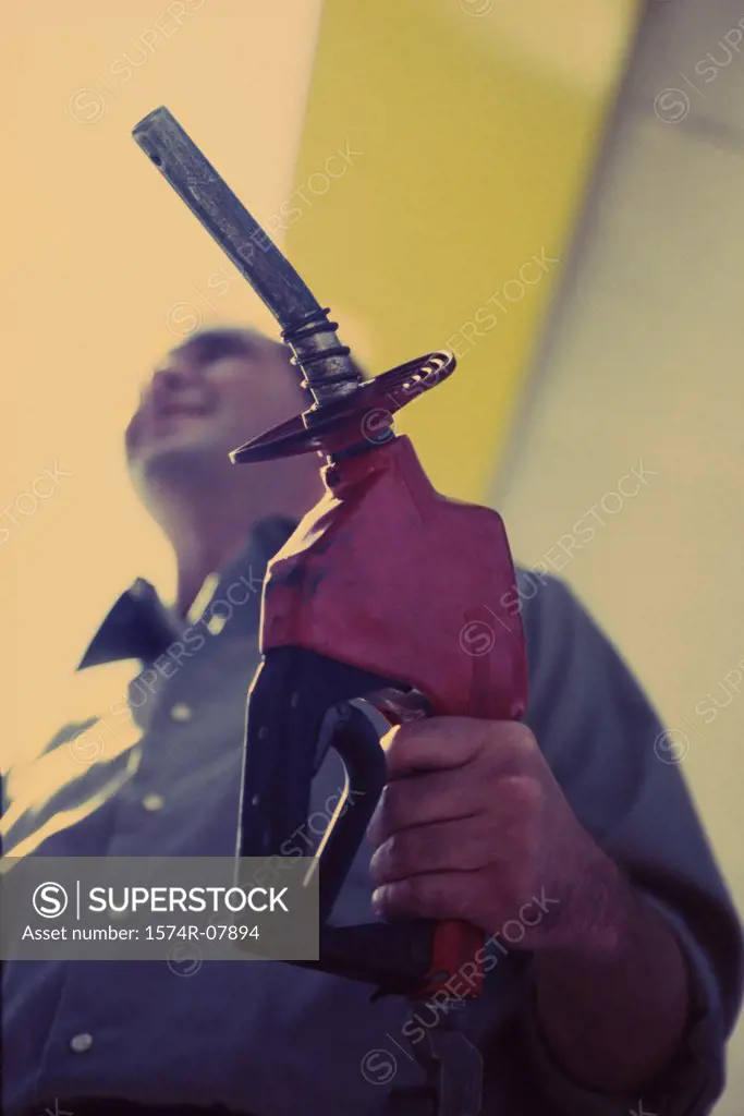 Low angle view of a gas station attendant holding a gas pump nozzle