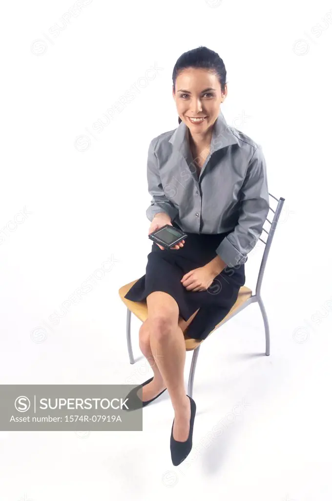 Portrait of a businesswoman sitting on a chair holding a hand held device