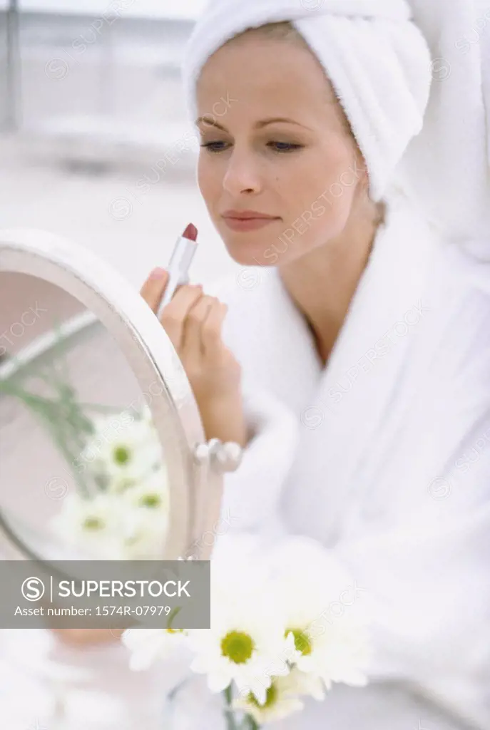 Young woman sitting in front of a mirror applying make-up