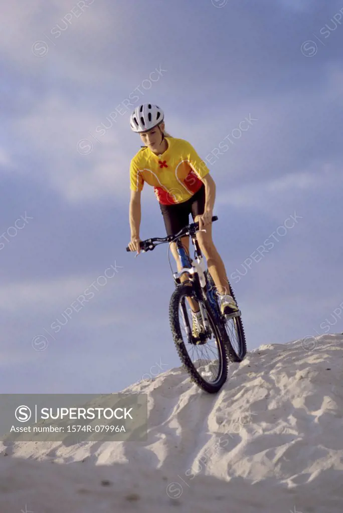 Low angle view of a young woman cycling on sand