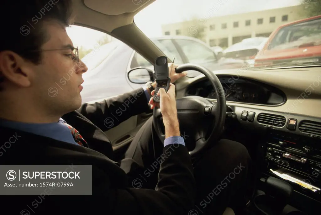 Side profile of a businessman dialing a mobile phone while in a car