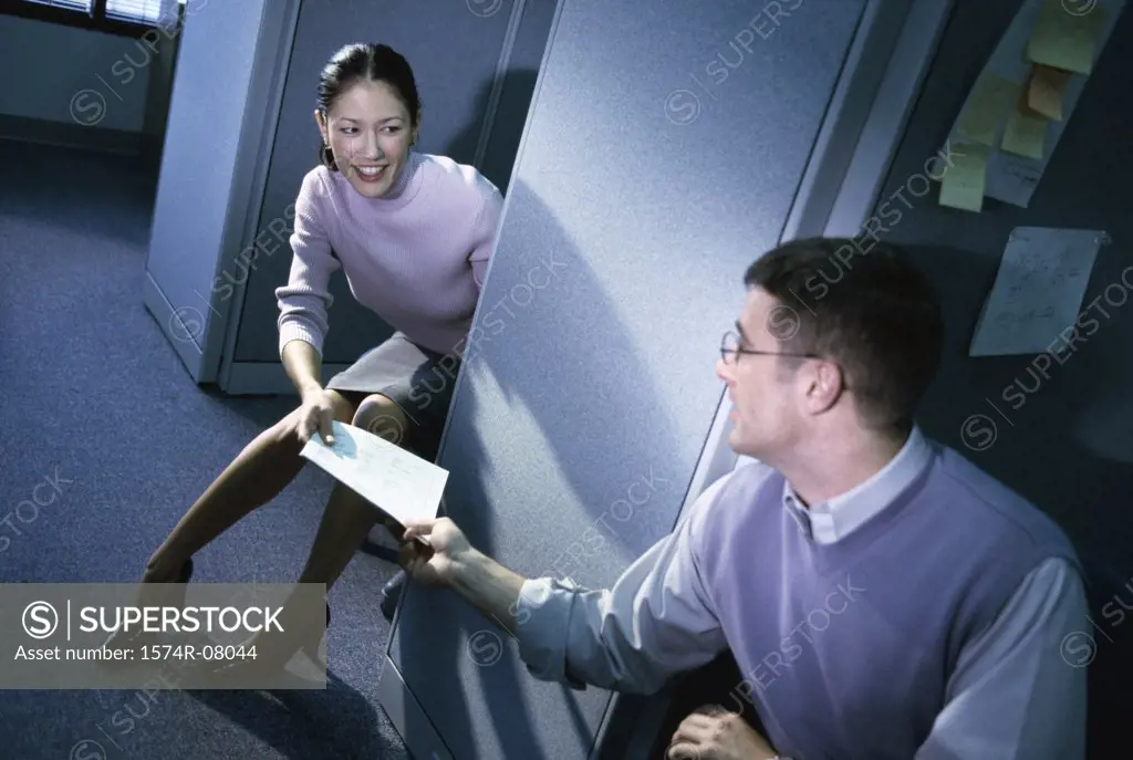 Businesswoman handing documents to a businessman in an office