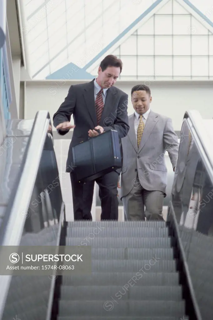 Two businessmen on the top of an escalator