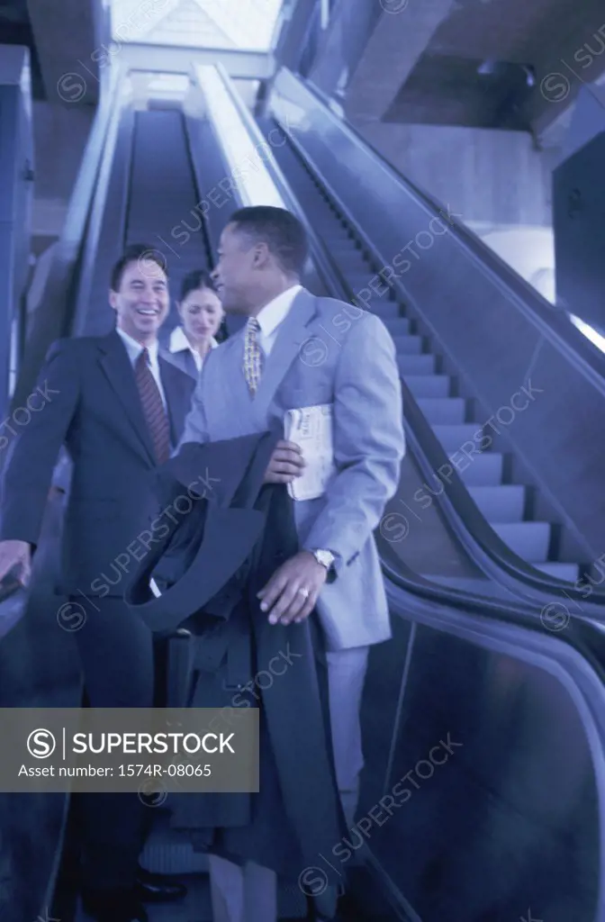Two businessmen and a businesswoman on an escalator