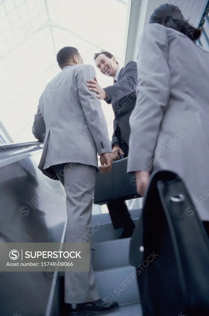 Low angle view of two businessmen and a businesswoman on an escalator