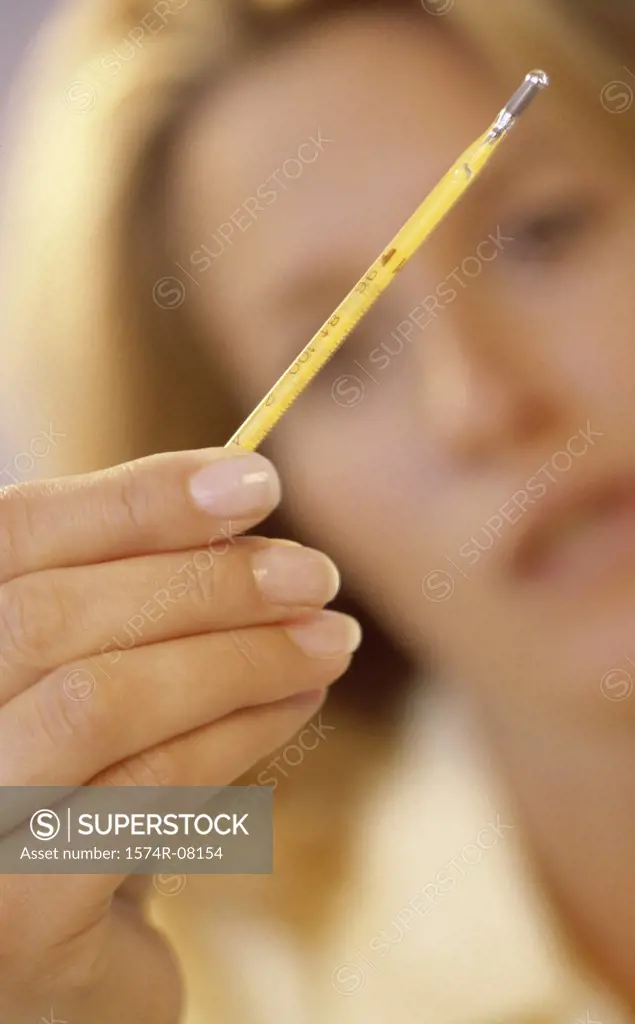 Close-up of a young woman holding a thermometer