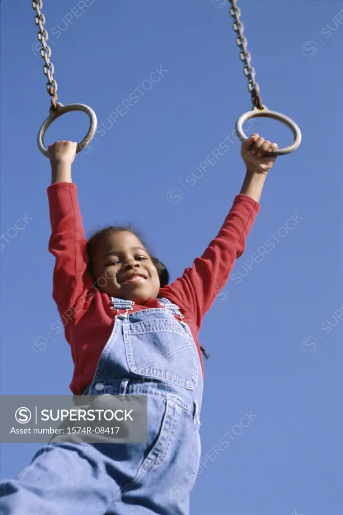 Low angle view of a girl hanging on rings