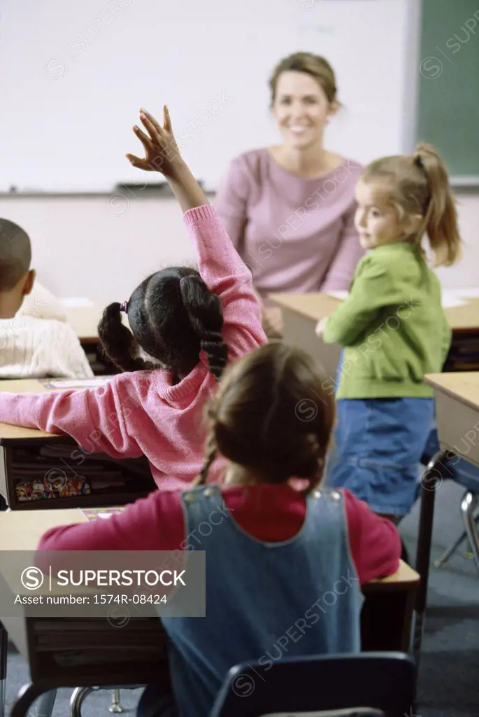 School children raising their hands in class
