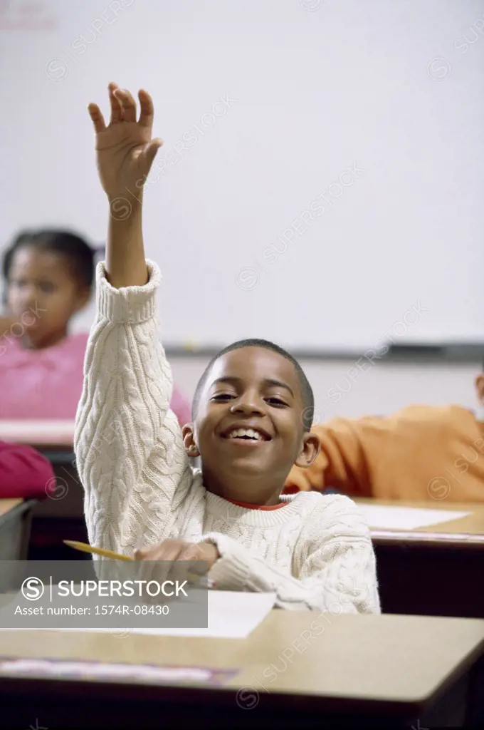 Portrait of a boy raising his hand in class
