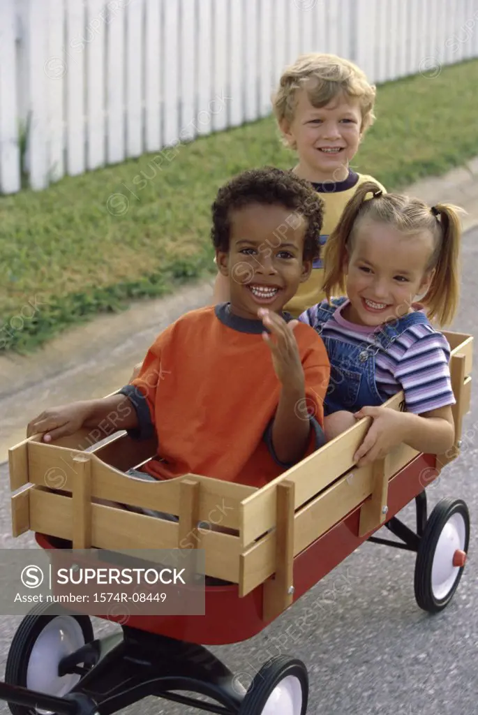 Portrait of two boys and a girl playing with a push cart