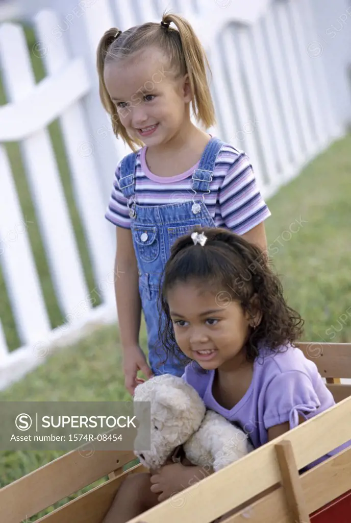 Two girls playing with a push cart
