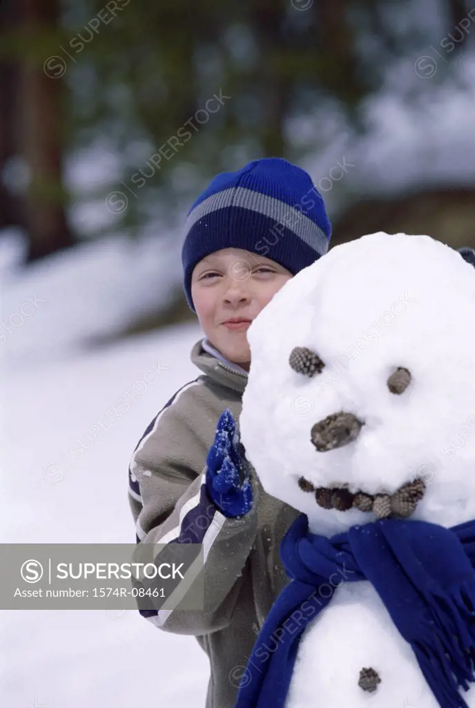 Portrait of a boy standing behind a snowman