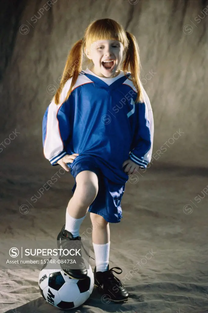 Portrait of a girl standing with her foot on a soccer ball