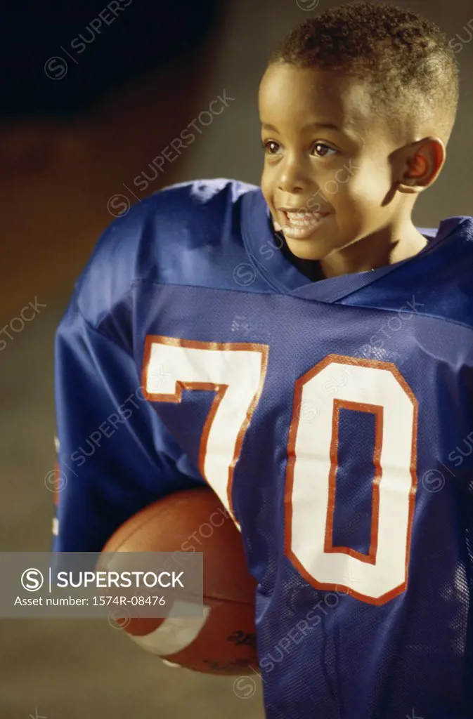 Boy in an oversized football uniform holding a ball
