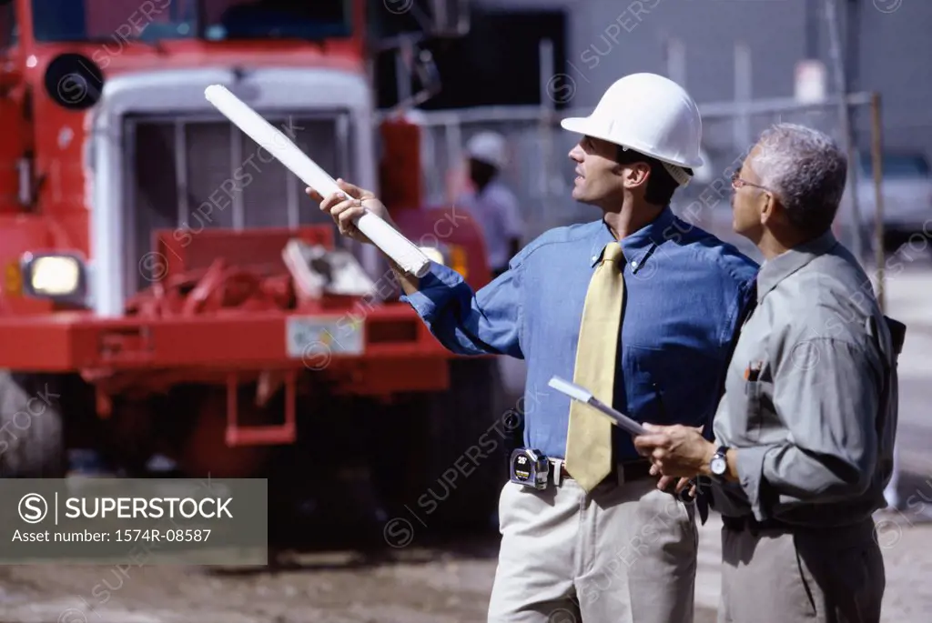 Side profile of two foremen discussing at a construction site