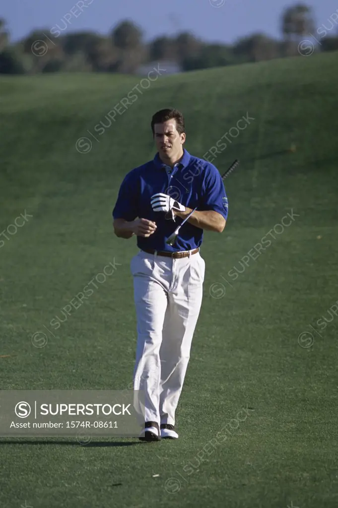 Man walking with a golf club on a golf course