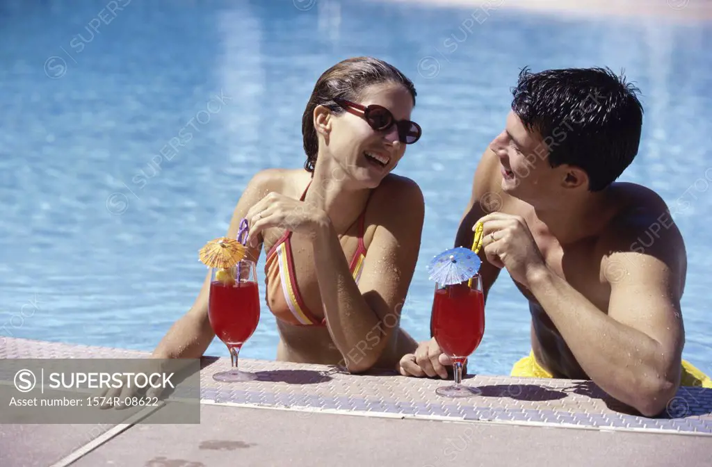 Young couple together in a swimming pool with drinks