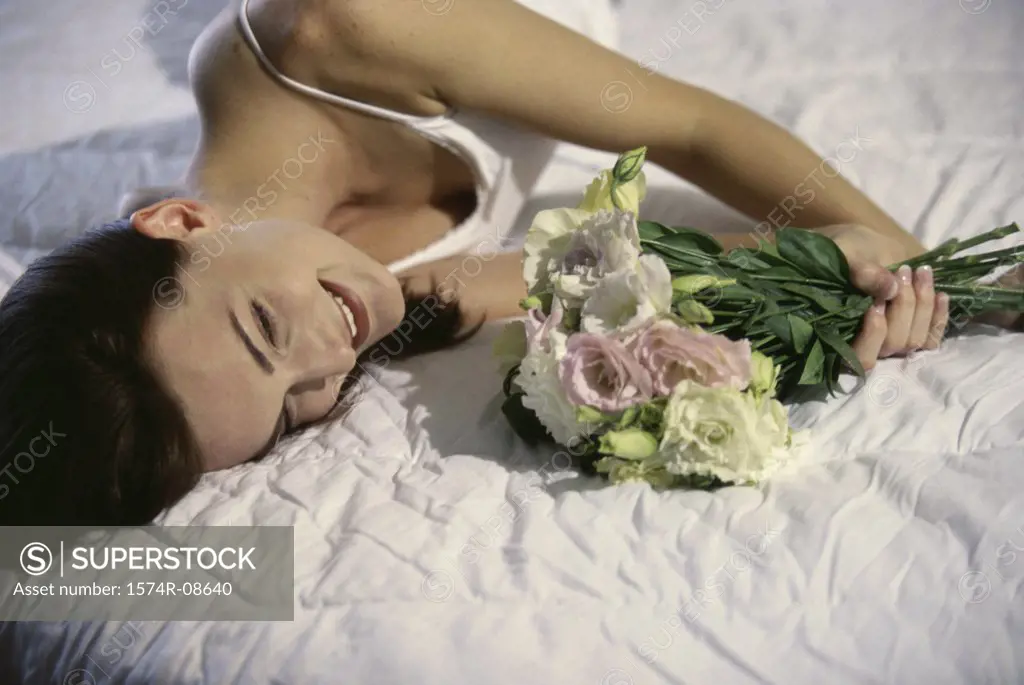 Young woman lying down holding a bouquet of flowers