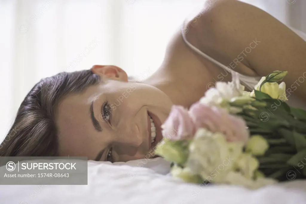 Portrait of a young woman lying down holding a bouquet of flowers