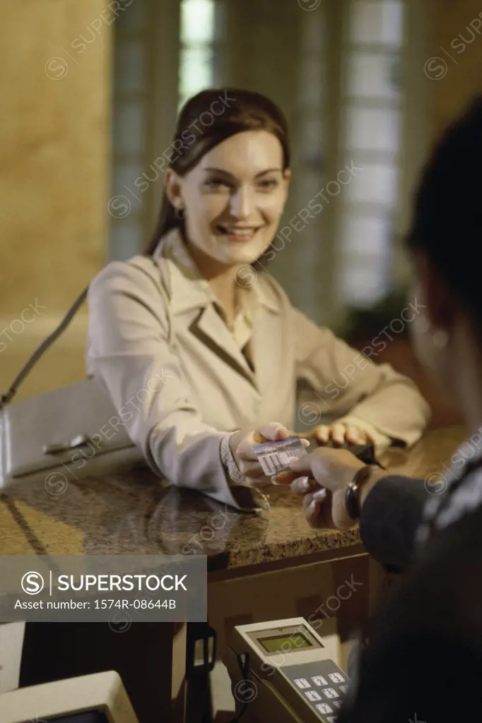 Businesswoman handing a credit card to a hotel clerk