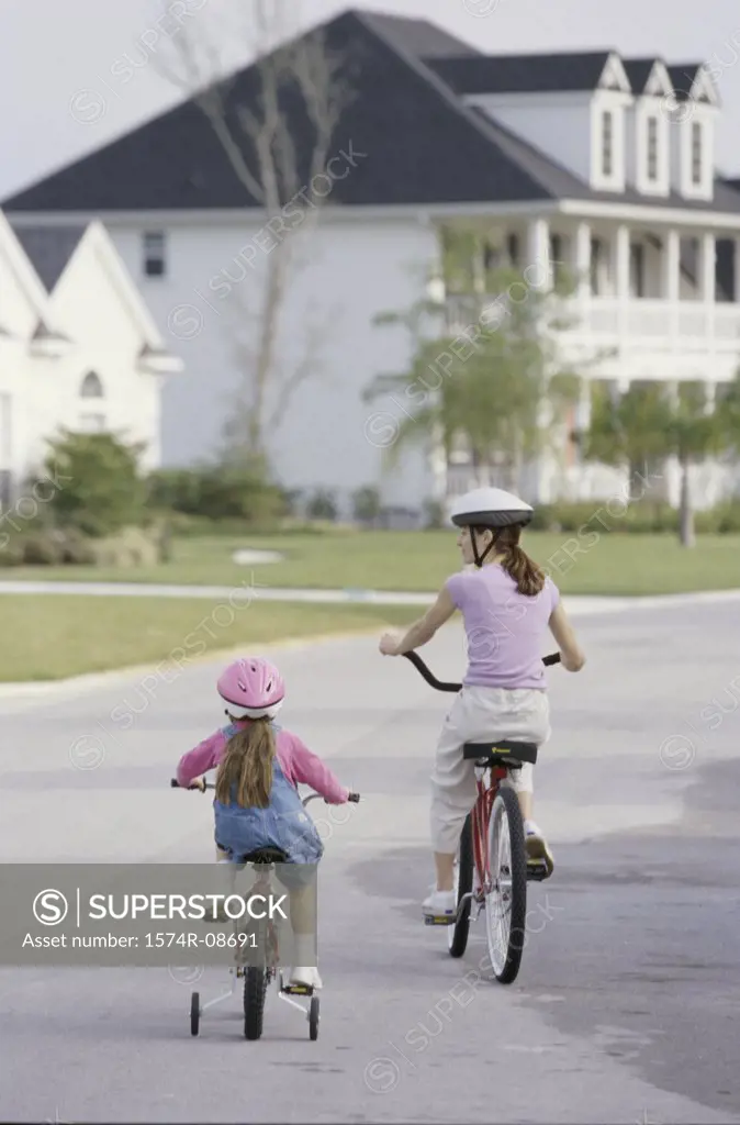 Rear view of a mother and daughter riding bicycles