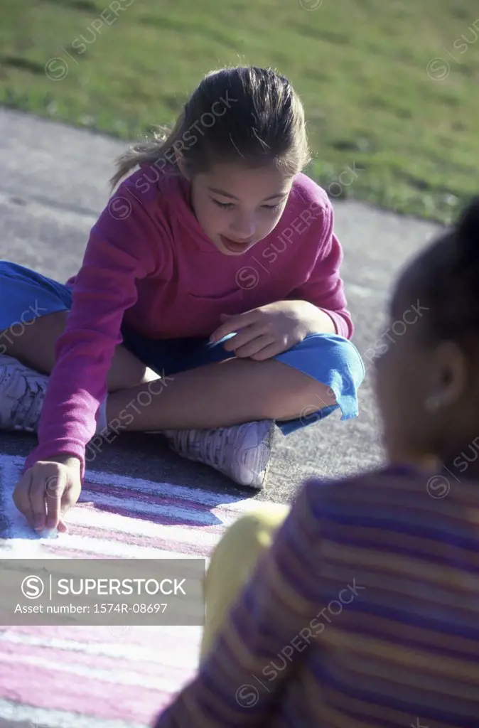 High angle view of two girls drawing with chalk on the floor