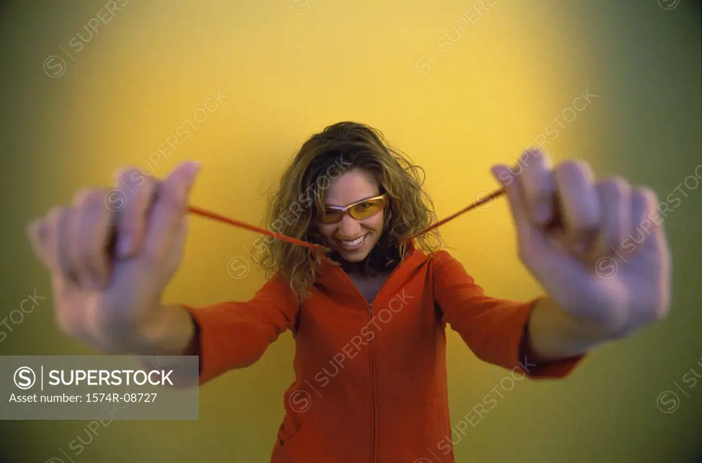 Portrait of a young woman holding strings of her hooded jacket