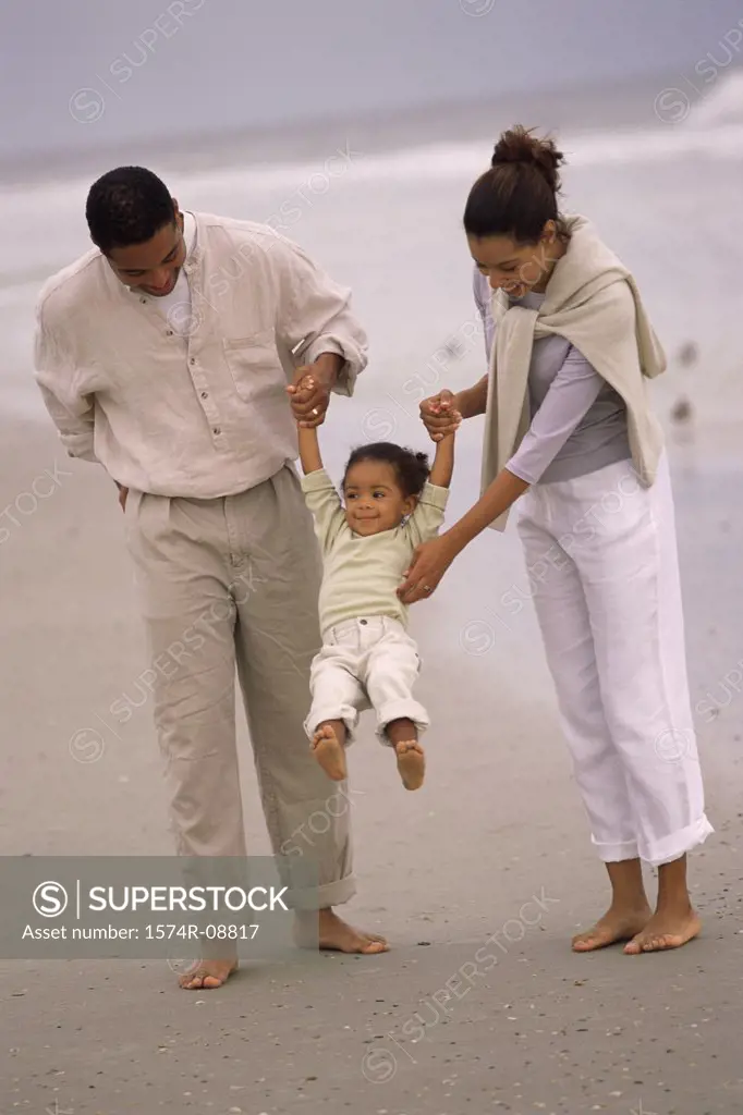 Father and mother walking with their daughter on the beach