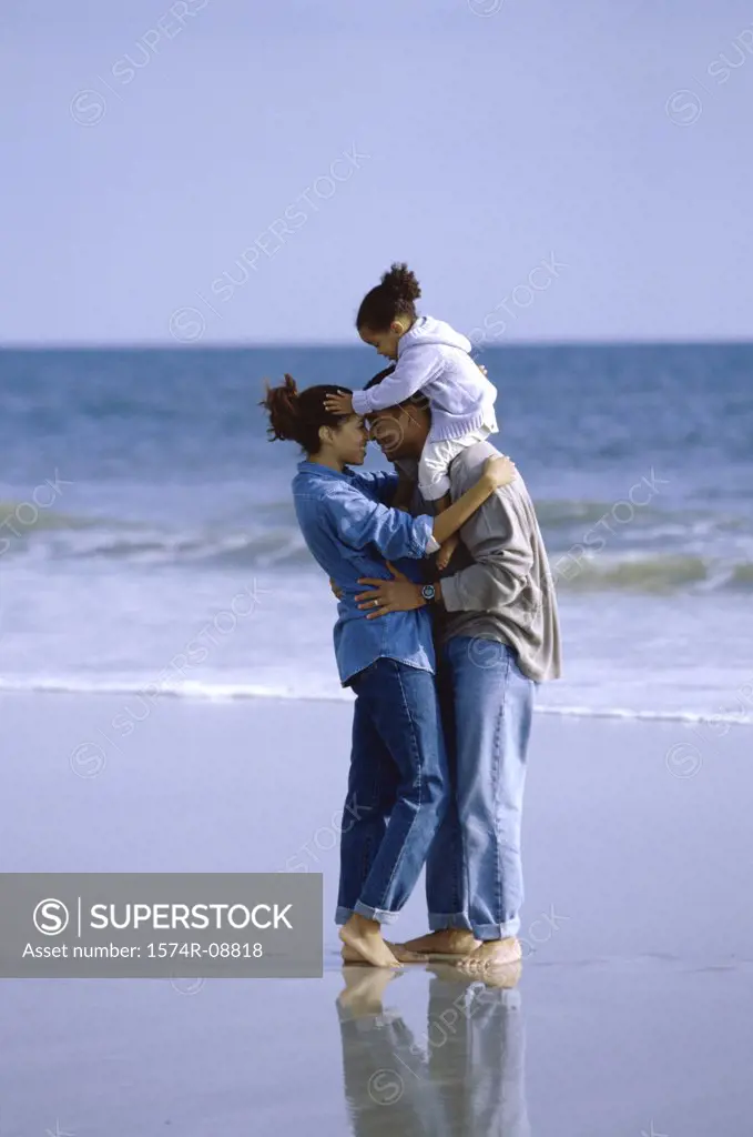 Father and mother on the beach carrying their daughter