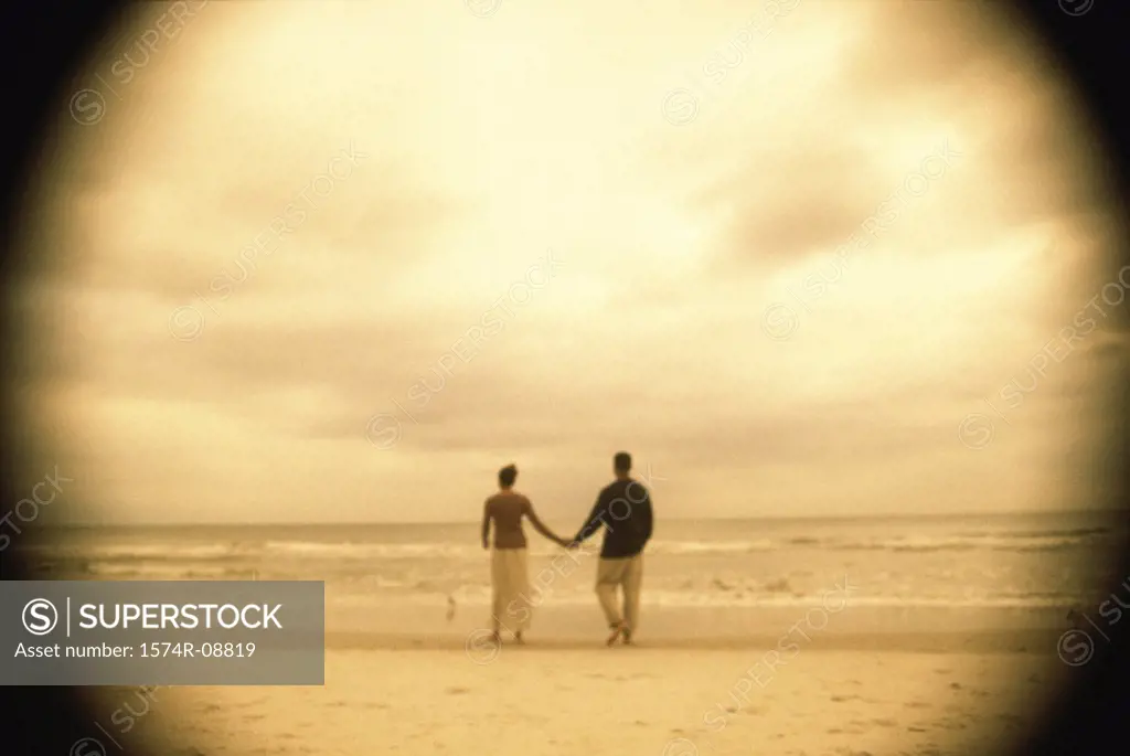 Rear view of a young couple holding hands on the beach